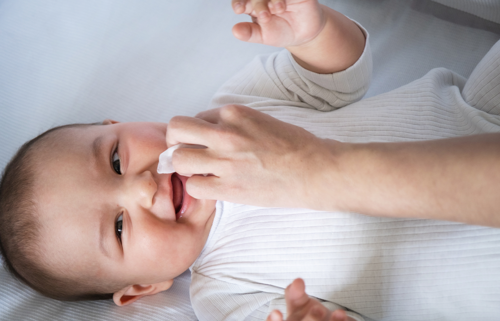Un parent nettoie le nez d’un bébé avec un mouche-bébé